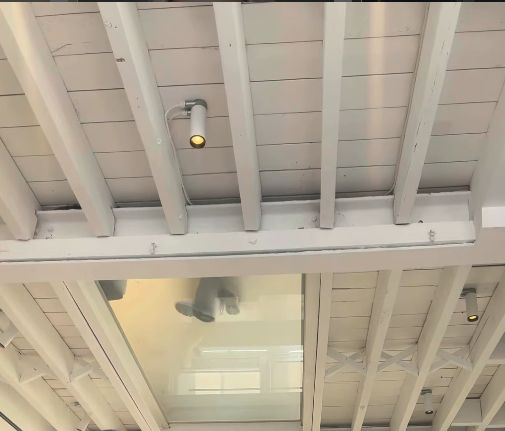 White ceiling beams and spotlights above the salon floor